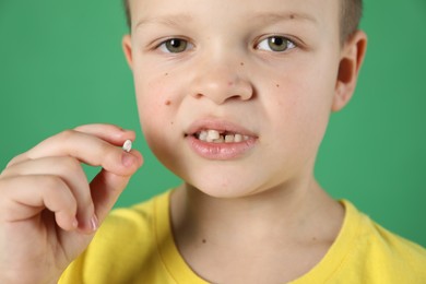 Photo of Cute little boy with missing tooth on green background, closeup. Waiting for tooth fairy