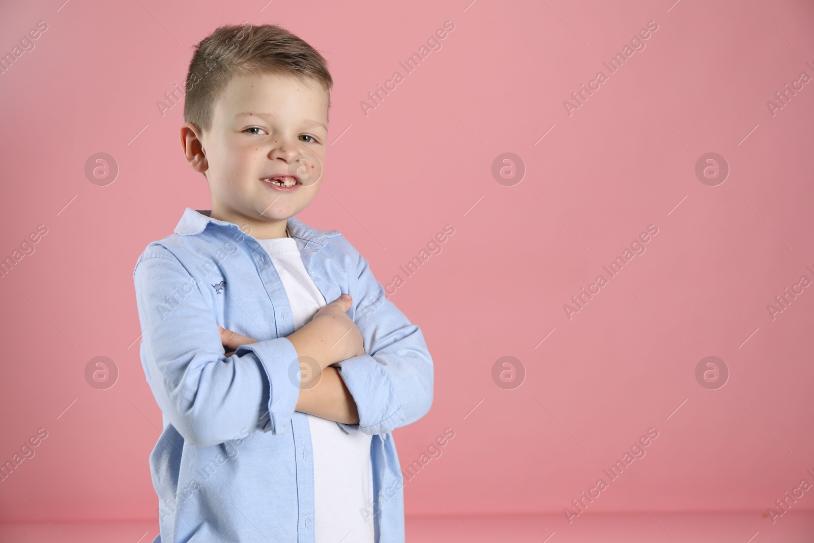 Photo of Cute little boy with missing tooth on pink background, space for text