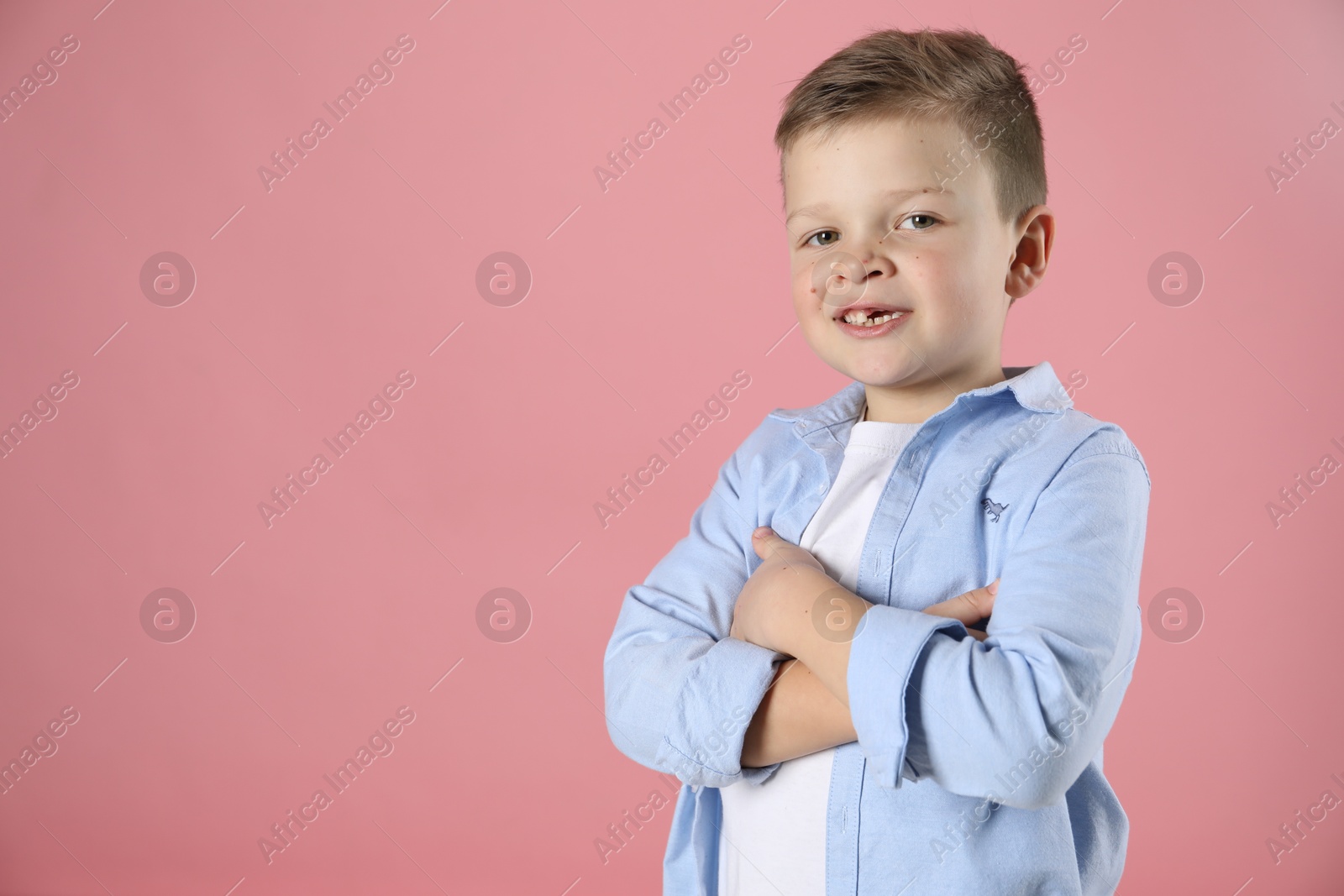 Photo of Cute little boy with missing tooth on pink background, space for text