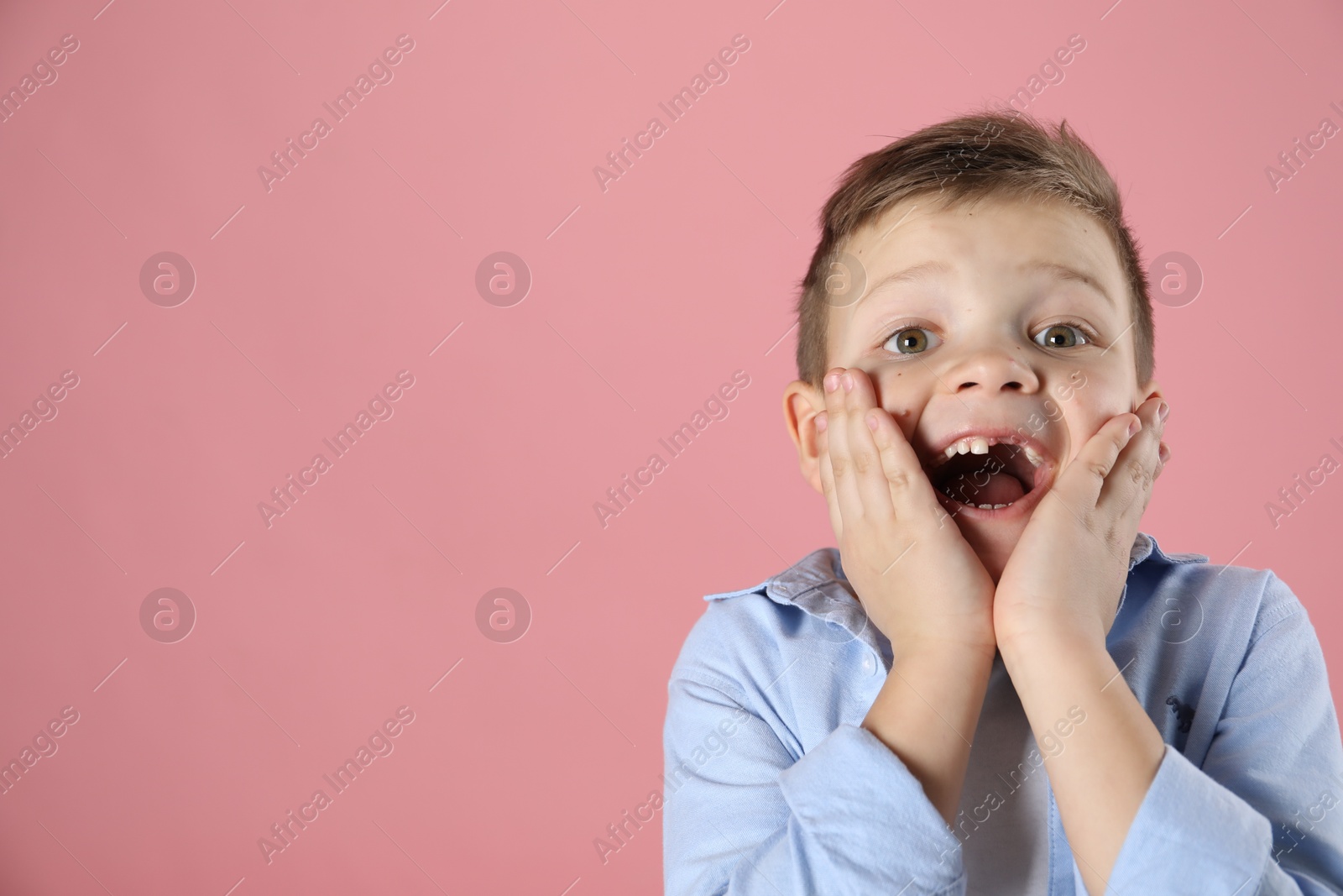 Photo of Cute little boy with missing tooth on pink background, space for text