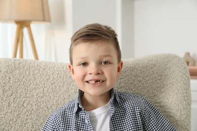 Photo of Cute little boy with missing tooth at home