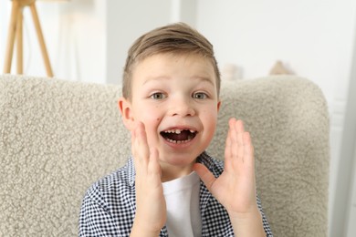 Photo of Cute little boy with missing tooth at home