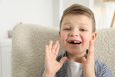 Photo of Cute little boy with missing tooth at home