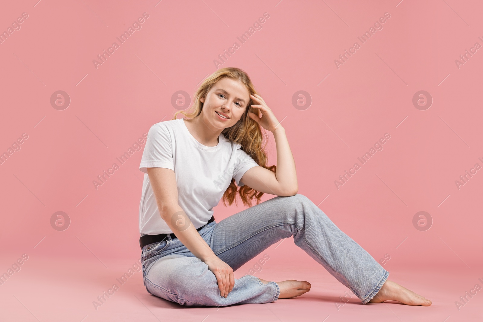 Photo of Smiling woman in stylish jeans on pink background