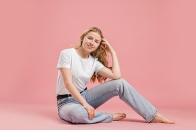 Photo of Smiling woman in stylish jeans on pink background