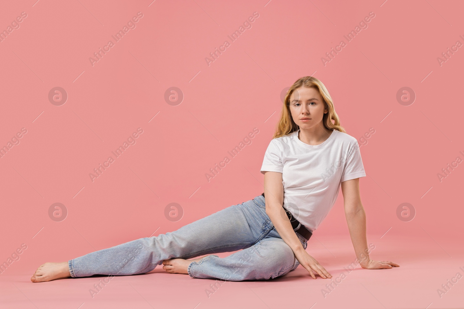 Photo of Woman in stylish jeans on pink background. Space for text