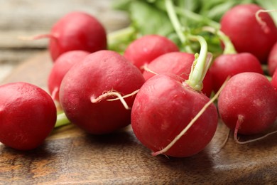 Photo of Many fresh radishes on wooden board, closeup