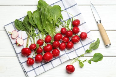 Photo of Many fresh radishes and knife on white wooden table, flat lay