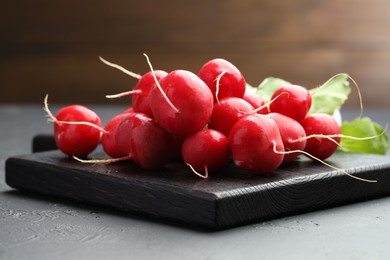 Photo of Many fresh radishes on dark textured table, closeup