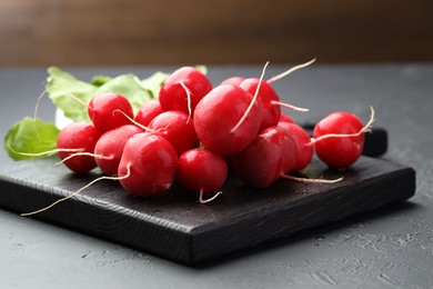 Photo of Many fresh radishes on dark textured table, closeup