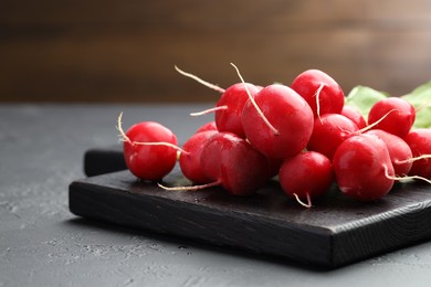 Photo of Many fresh radishes on dark textured table, closeup