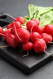 Photo of Many fresh radishes on dark textured table, closeup