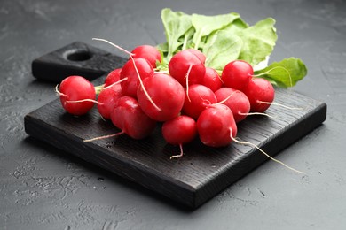 Photo of Many fresh radishes on dark textured table, closeup