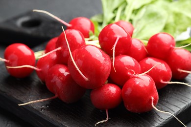Photo of Many fresh radishes on dark table, closeup