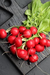 Photo of Many fresh radishes on dark textured table, top view