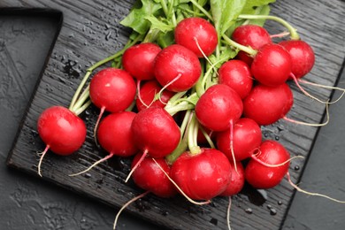 Photo of Many fresh radishes on dark textured table, top view