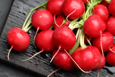 Photo of Many fresh radishes on dark table, above view