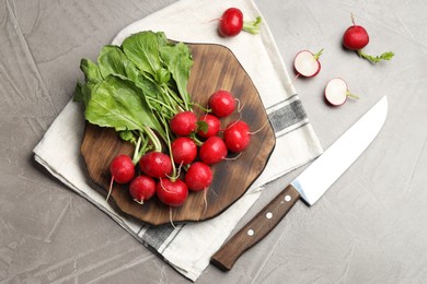 Photo of Many fresh radishes and knife on grey textured table, flat lay