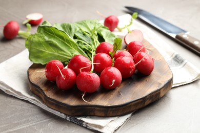 Photo of Many fresh radishes on grey textured table, closeup