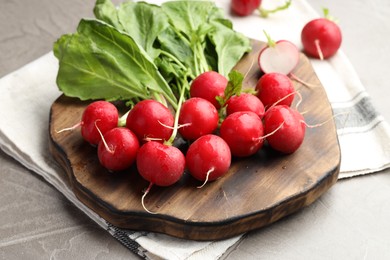 Photo of Many fresh radishes on grey textured table, closeup