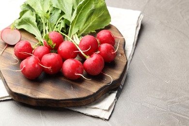 Photo of Many fresh radishes on grey textured table, closeup. Space for text