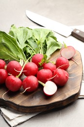 Photo of Many fresh radishes on grey textured table, closeup