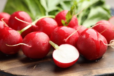 Photo of Many fresh radishes on wooden board, closeup