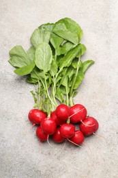 Photo of Many fresh radishes on grey textured table, top view