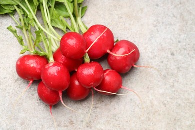 Photo of Many fresh radishes on grey textured table, above view