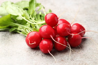 Photo of Many fresh radishes on grey textured table, closeup