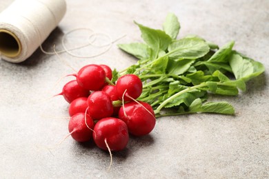 Photo of Many fresh radishes on grey textured table, closeup