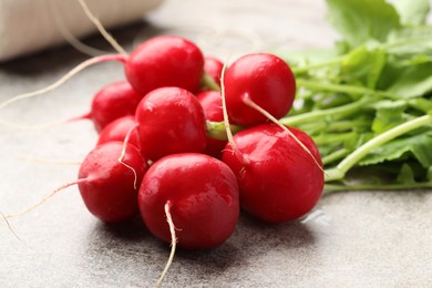Photo of Many fresh radishes on grey textured table, closeup