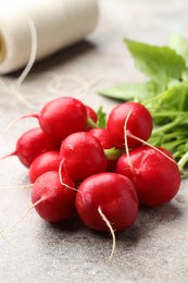 Photo of Many fresh radishes on grey textured table, closeup