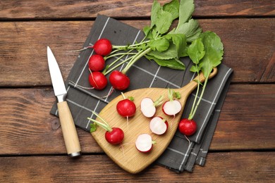 Photo of Many fresh radishes and knife on wooden table, flat lay