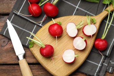 Photo of Many fresh radishes and knife on wooden table, flat lay