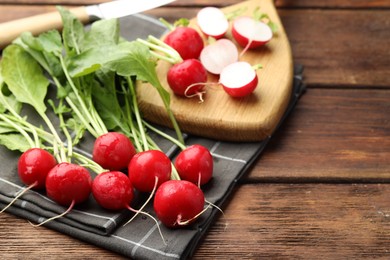 Photo of Many fresh radishes on wooden table, closeup. Space for text