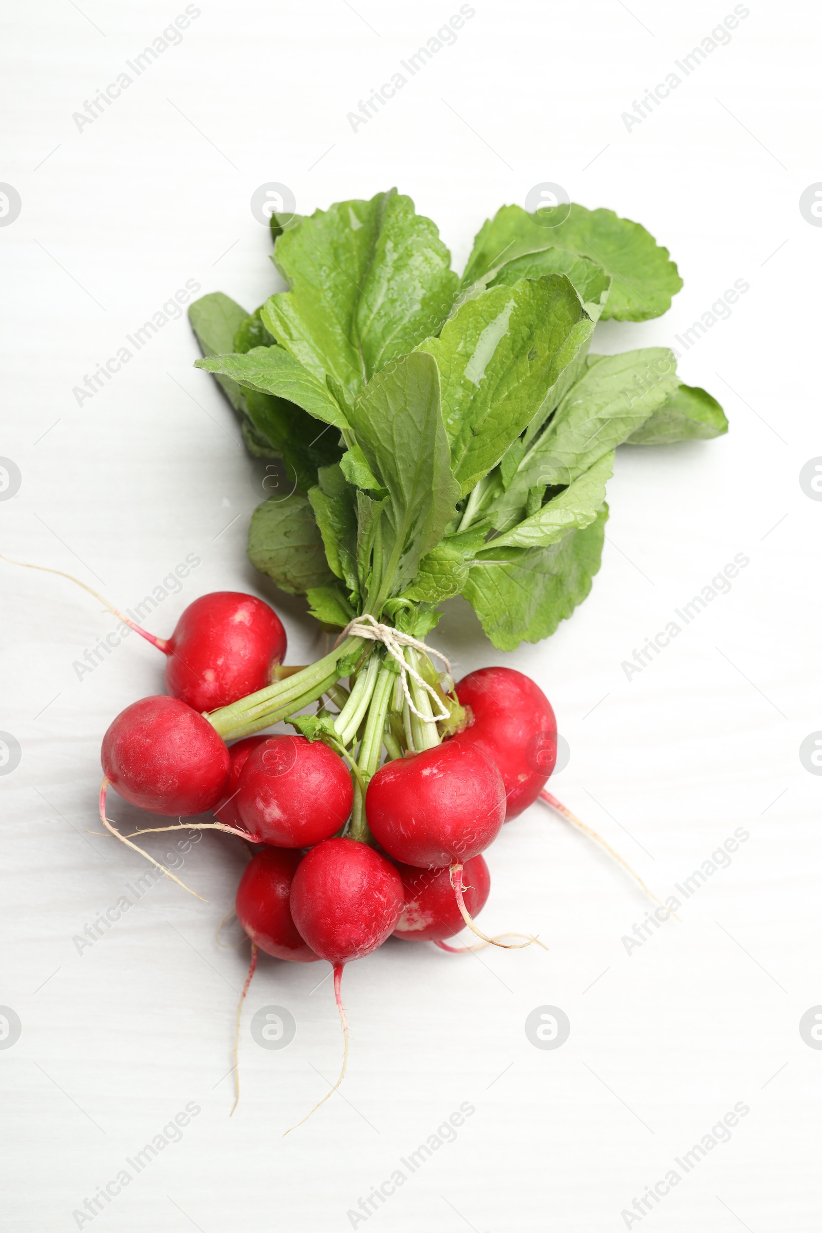 Photo of Bunch of fresh radishes on white wooden table, top view