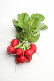 Photo of Bunch of fresh radishes on white wooden table, top view