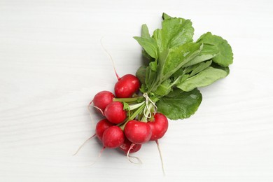 Photo of Bunch of fresh radishes on white wooden table, top view