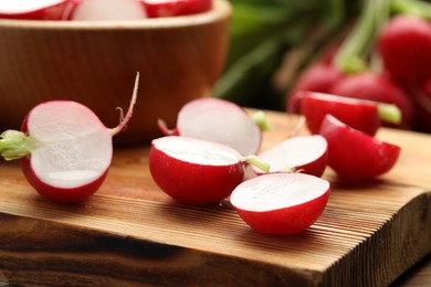 Photo of Fresh cut radishes on wooden board, closeup
