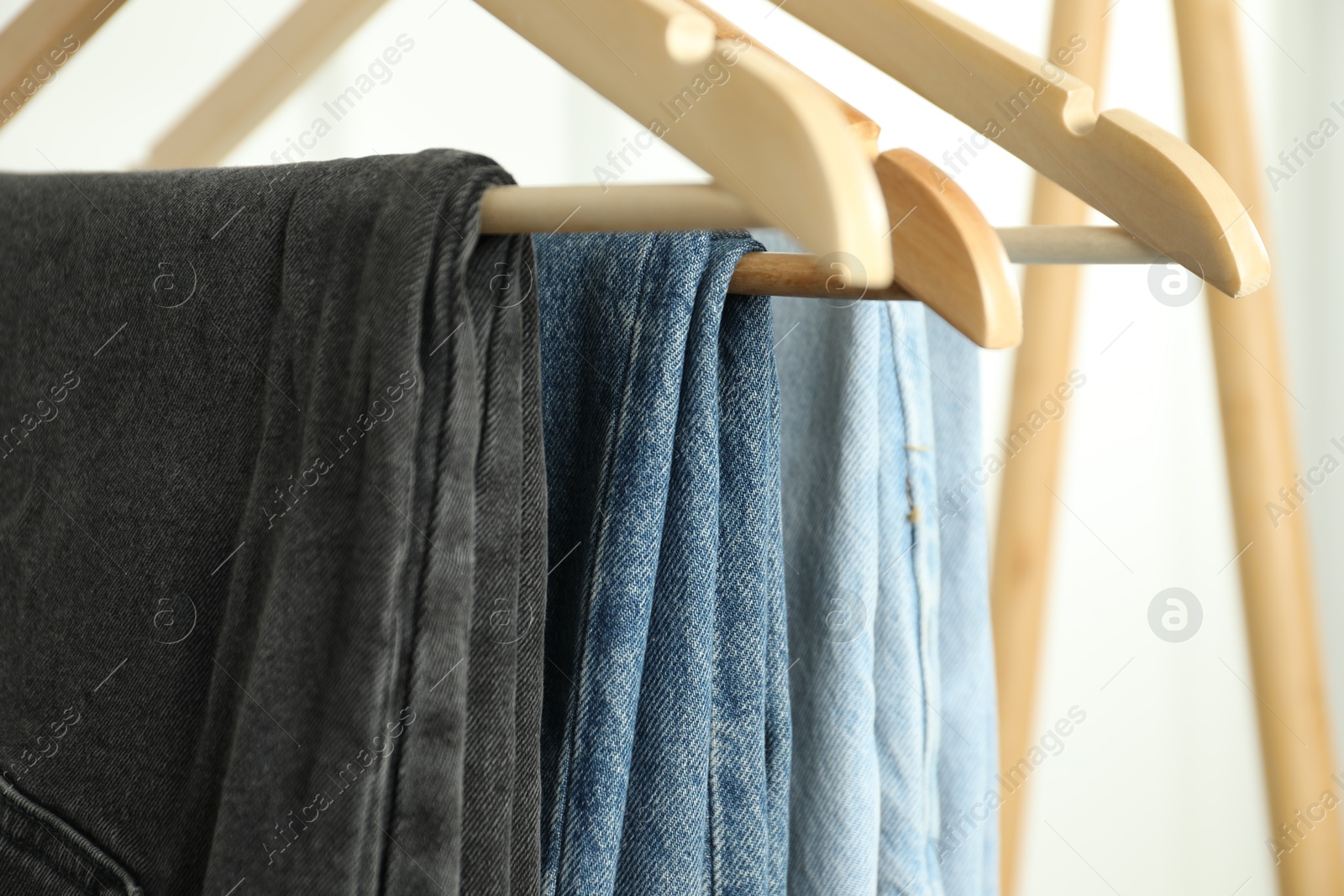 Photo of Many stylish jeans hanging against white background, closeup