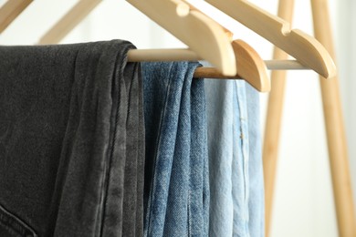 Photo of Many stylish jeans hanging against white background, closeup