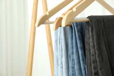 Photo of Many stylish jeans hanging against white background, closeup