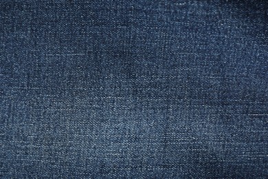 Photo of Texture of dark blue jeans as background, top view