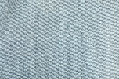 Photo of Texture of light blue jeans as background, top view