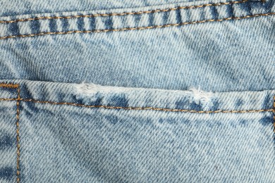 Photo of Ripped light blue jeans with pocket as background, top view