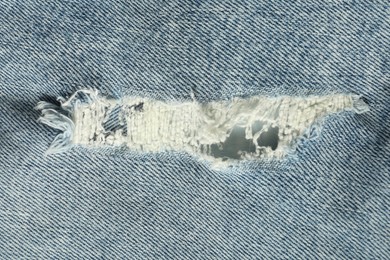 Photo of Texture of ripped light blue jeans as background, top view