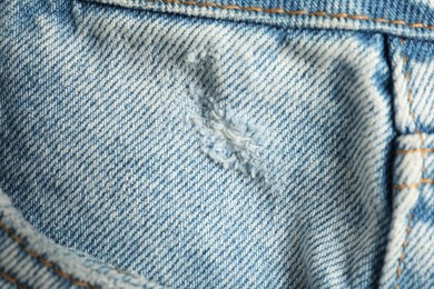 Photo of Ripped light blue jeans with pocket as background, closeup