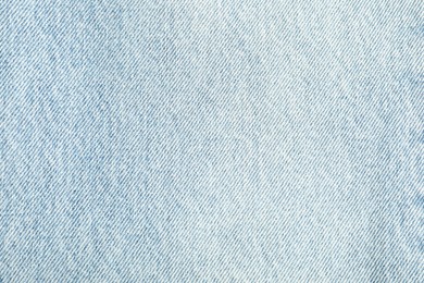 Photo of Texture of light blue jeans as background, top view