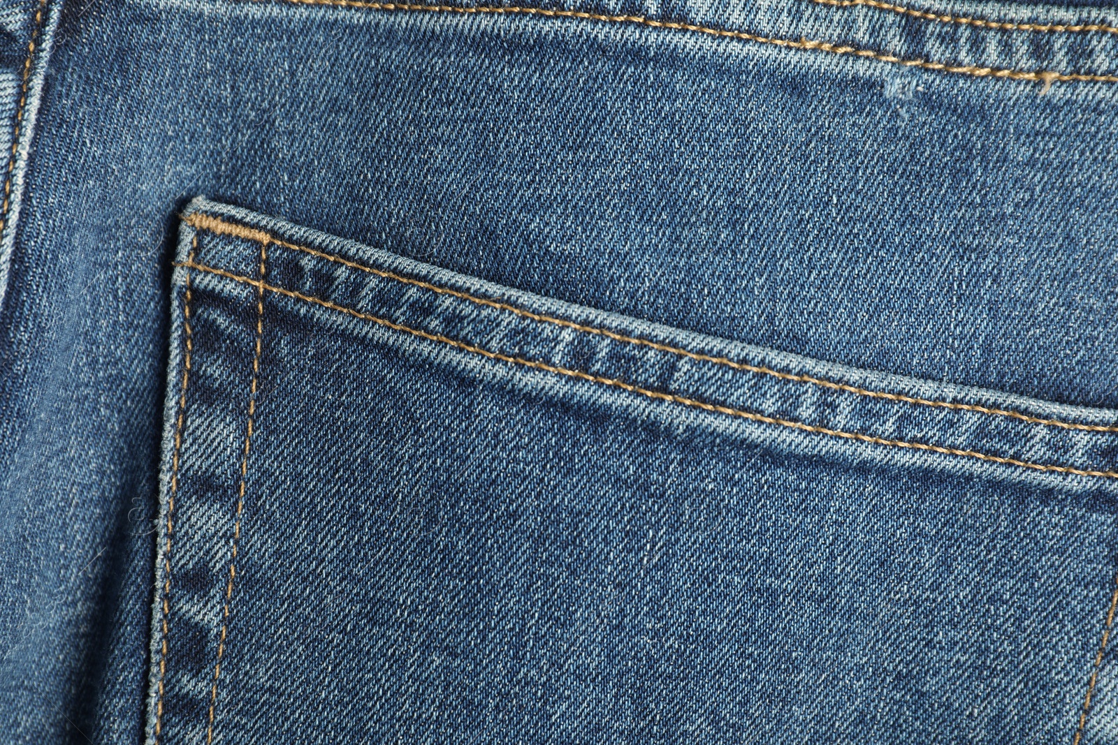 Photo of Stylish blue jeans with pocket as background, top view